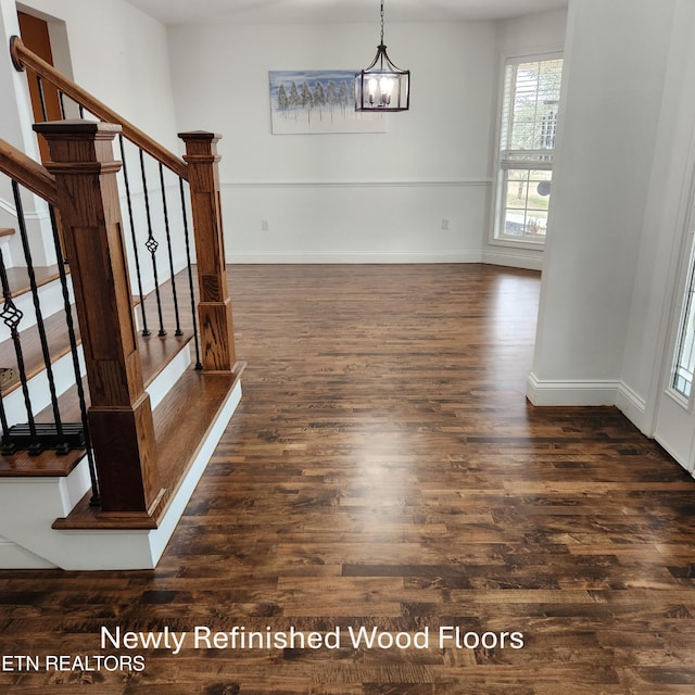 unfurnished dining area with dark wood-type flooring and an inviting chandelier