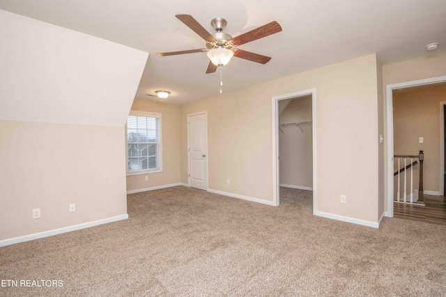 unfurnished bedroom featuring a spacious closet, ceiling fan, light colored carpet, vaulted ceiling, and a closet