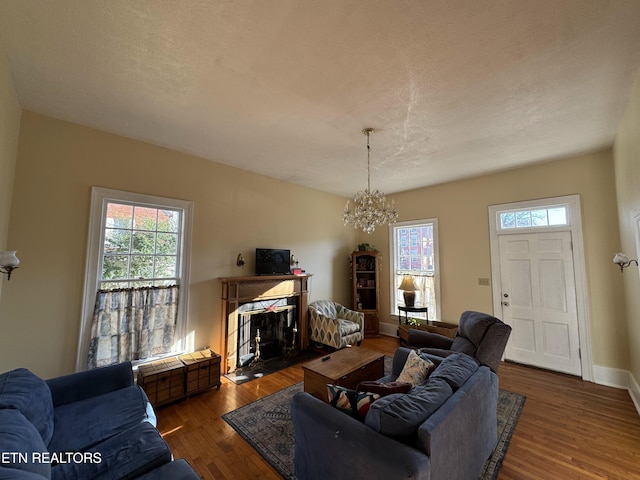 living room with a chandelier, a textured ceiling, and dark wood-type flooring