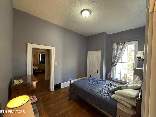 bedroom with dark hardwood / wood-style flooring and a textured ceiling