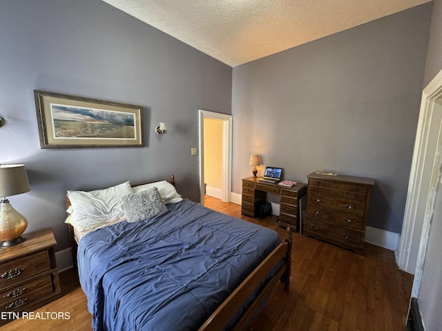 bedroom featuring dark hardwood / wood-style flooring, a textured ceiling, and vaulted ceiling