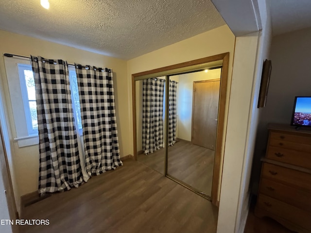 bedroom featuring hardwood / wood-style flooring, a textured ceiling, and a closet