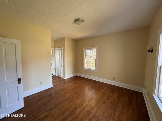 empty room with a textured ceiling and dark wood-type flooring