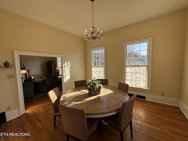 dining area with a textured ceiling, dark hardwood / wood-style flooring, and a notable chandelier