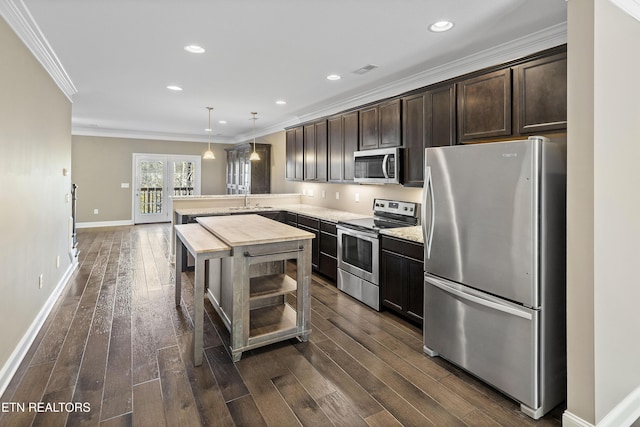 kitchen featuring dark wood-type flooring, hanging light fixtures, ornamental molding, appliances with stainless steel finishes, and dark brown cabinetry