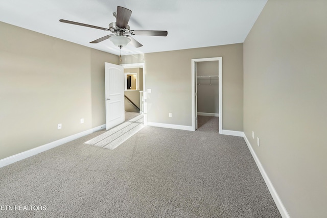 unfurnished bedroom featuring carpet flooring, a closet, a spacious closet, and ceiling fan