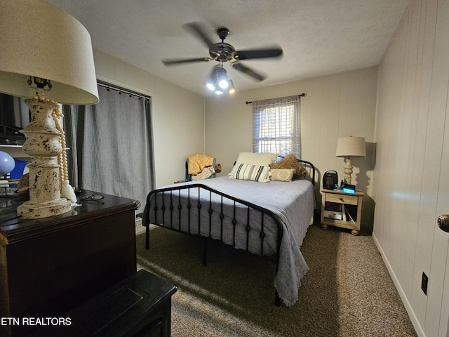 carpeted bedroom featuring ceiling fan, wood walls, and a textured ceiling