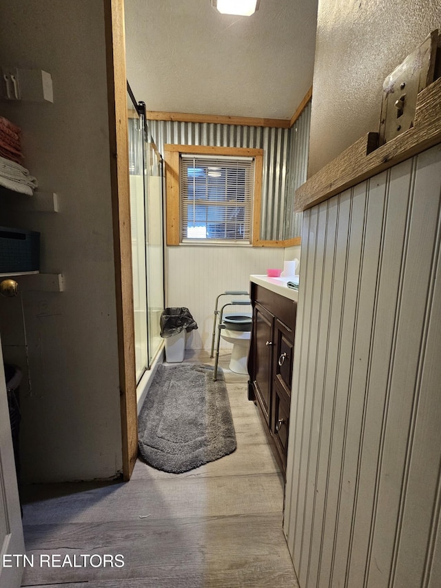 bathroom with hardwood / wood-style floors, vanity, toilet, a textured ceiling, and an enclosed shower