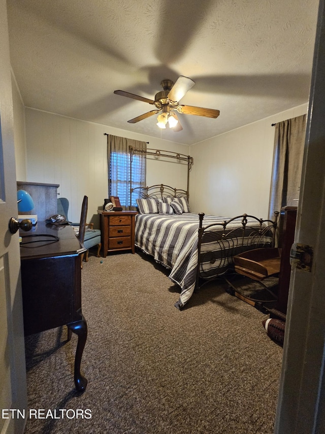 bedroom featuring a textured ceiling, carpet floors, ceiling fan, and wooden walls