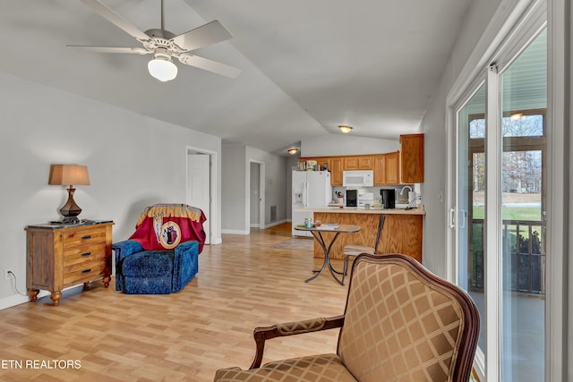 living area with ceiling fan, light wood-type flooring, and vaulted ceiling