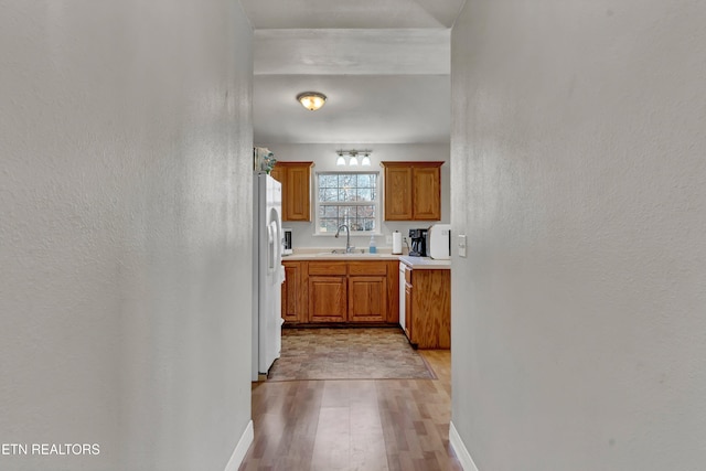 kitchen featuring white refrigerator with ice dispenser, light hardwood / wood-style floors, and sink