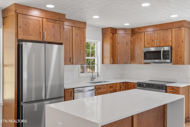 kitchen with appliances with stainless steel finishes, sink, and a textured ceiling