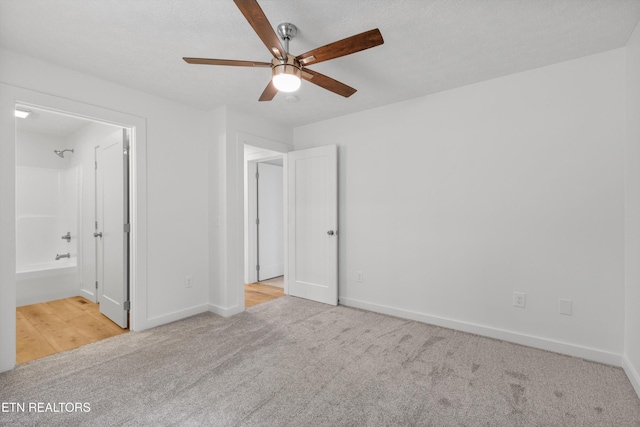 unfurnished bedroom with ensuite bathroom, light colored carpet, and ceiling fan