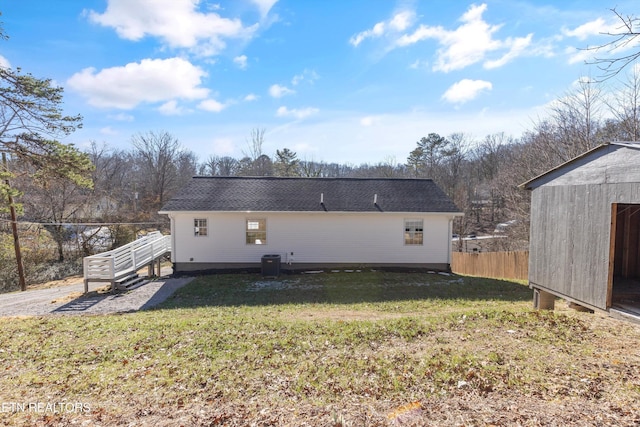 back of property with an outbuilding, central air condition unit, and a yard