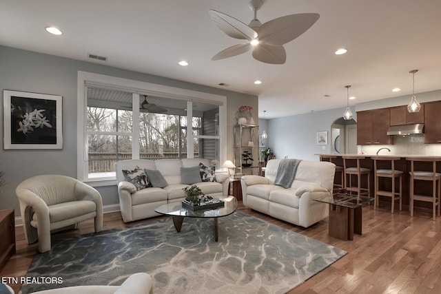 living room featuring ceiling fan and dark hardwood / wood-style flooring