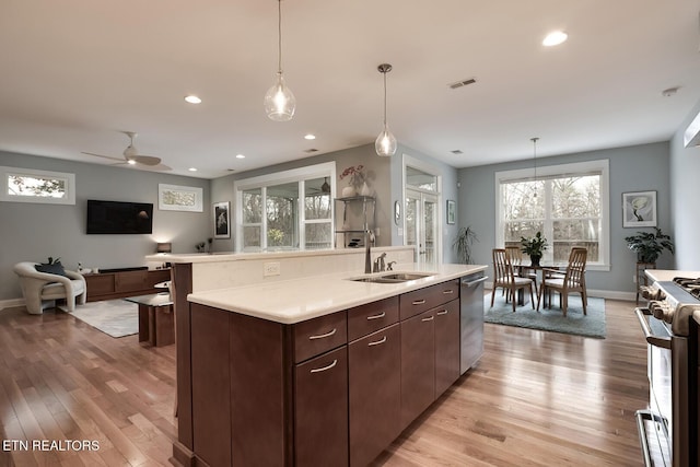 kitchen featuring appliances with stainless steel finishes, sink, hanging light fixtures, a kitchen island with sink, and dark brown cabinets