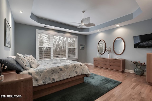 bedroom featuring a raised ceiling, ceiling fan, and light hardwood / wood-style floors