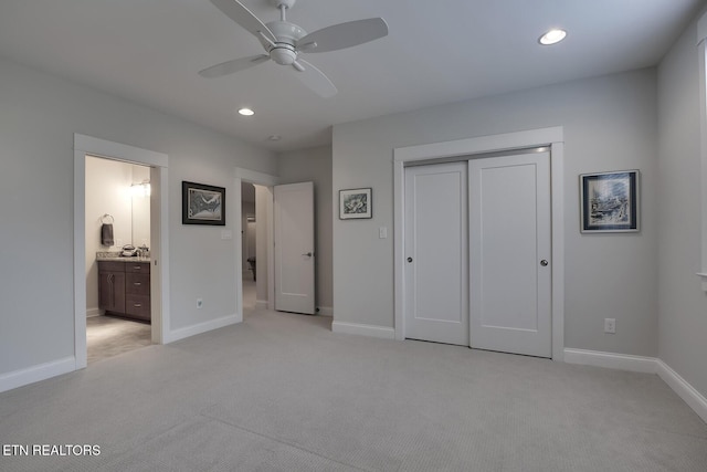 unfurnished bedroom featuring light carpet, a closet, ceiling fan, and ensuite bathroom