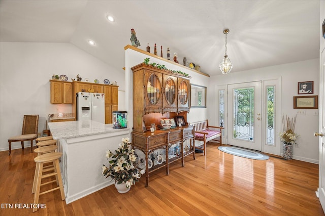 foyer with a notable chandelier, lofted ceiling, and light hardwood / wood-style flooring