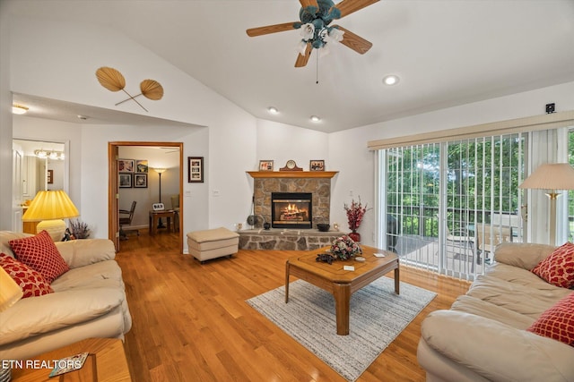 living room featuring ceiling fan, light wood-type flooring, a fireplace, and high vaulted ceiling