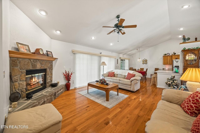 living room with ceiling fan, a fireplace, light hardwood / wood-style floors, and vaulted ceiling