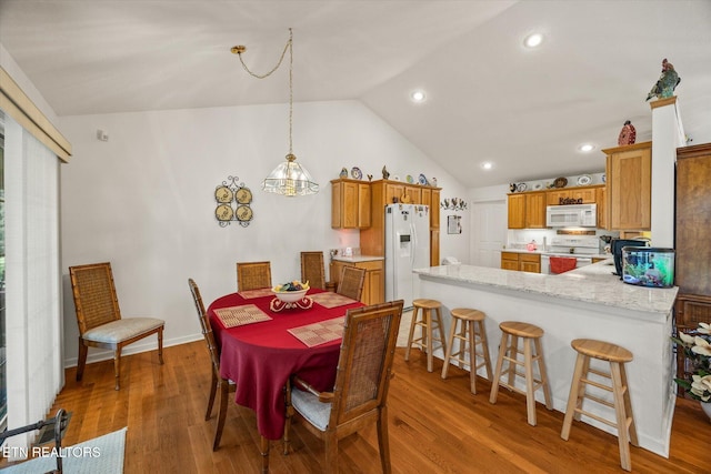 dining room with wood-type flooring and vaulted ceiling