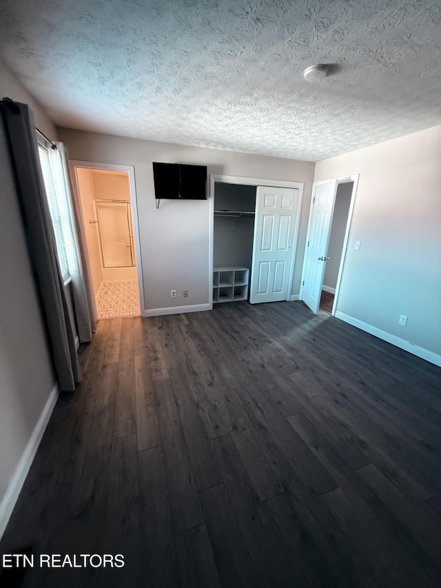 unfurnished bedroom with a textured ceiling and dark hardwood / wood-style flooring