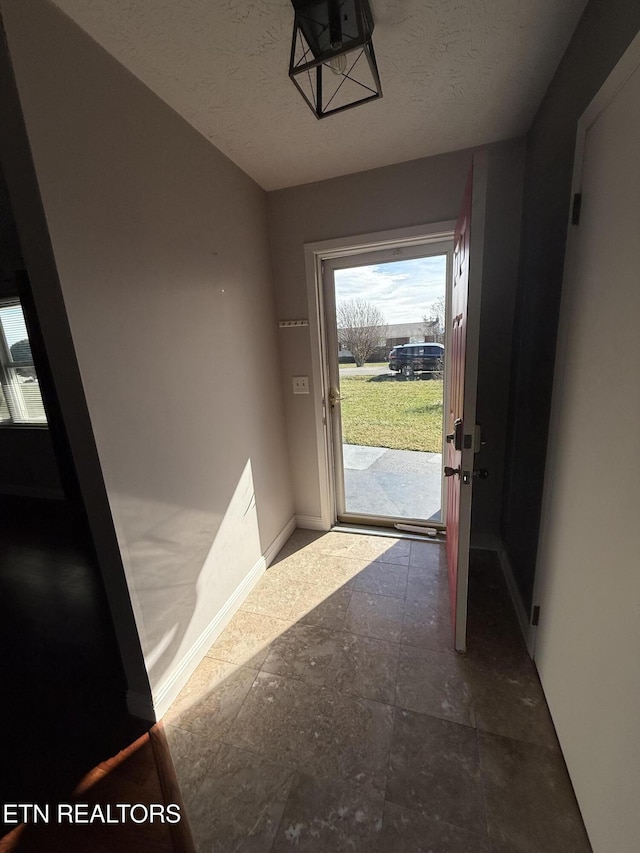 doorway to outside with a textured ceiling