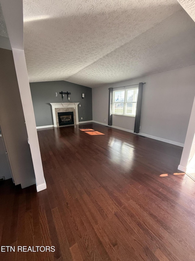 unfurnished living room with a textured ceiling, dark hardwood / wood-style flooring, and vaulted ceiling