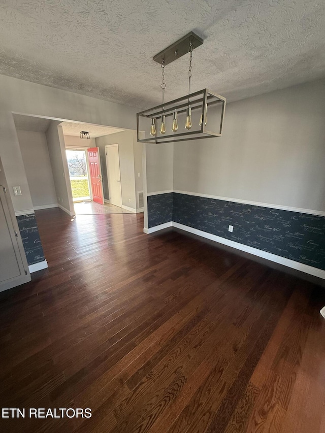 unfurnished dining area with dark hardwood / wood-style floors and a textured ceiling