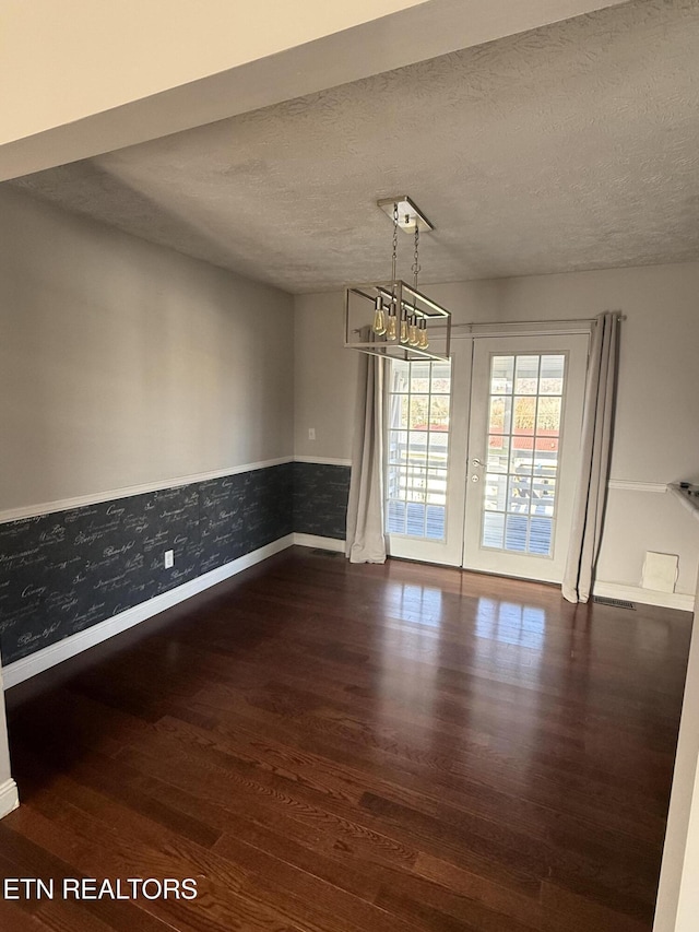 empty room featuring a chandelier, a textured ceiling, and dark hardwood / wood-style floors