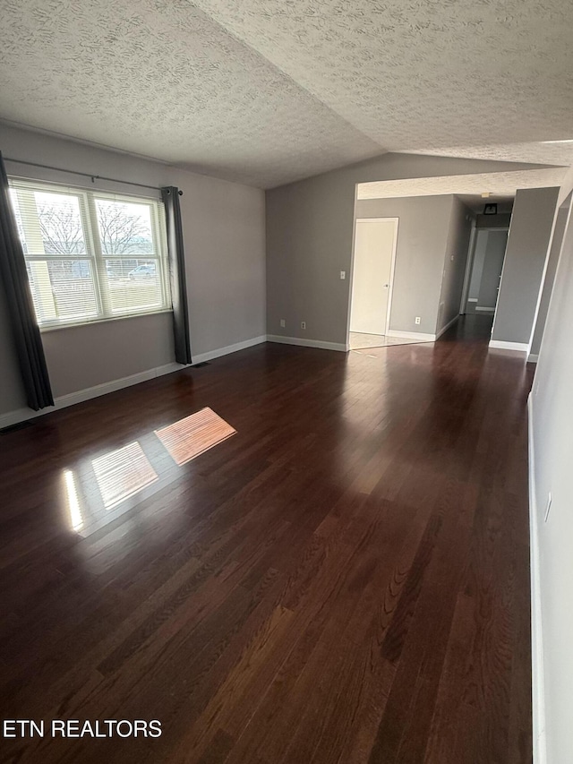 spare room featuring lofted ceiling, a textured ceiling, and dark wood-type flooring