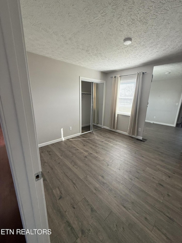 unfurnished bedroom with a closet, dark wood-type flooring, and a textured ceiling