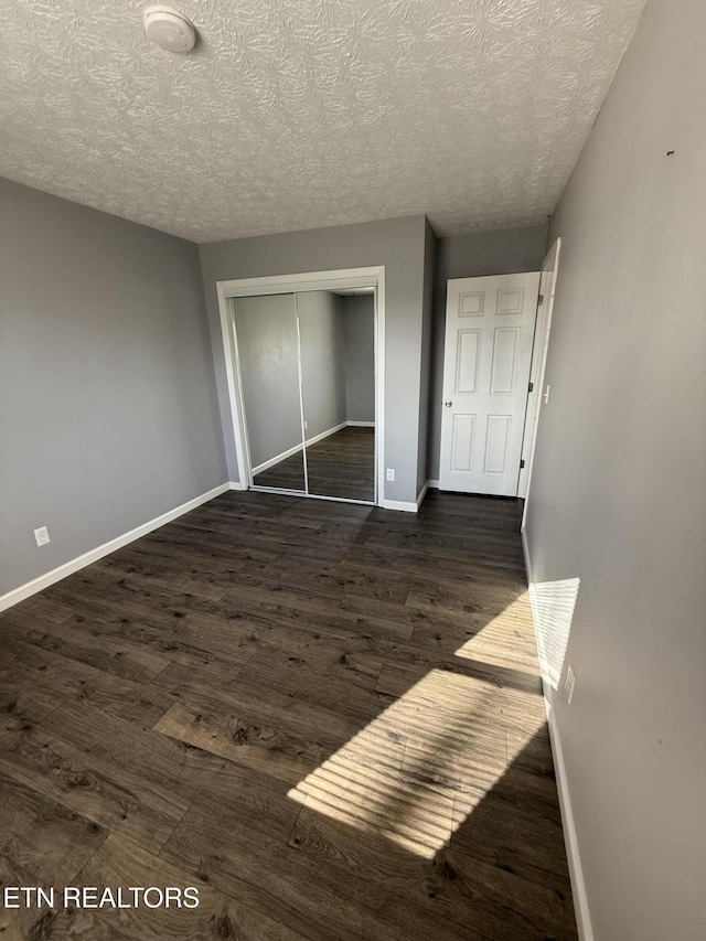 unfurnished bedroom with a closet, dark hardwood / wood-style flooring, and a textured ceiling