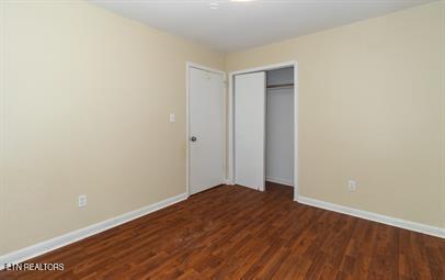 unfurnished bedroom with a closet and dark wood-type flooring