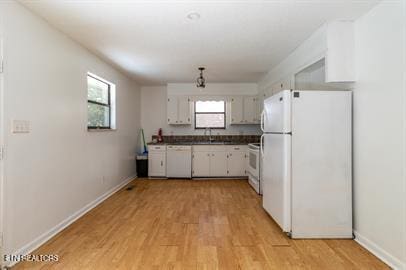 kitchen featuring white appliances, light hardwood / wood-style flooring, white cabinetry, and a wealth of natural light