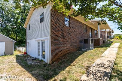 view of side of property with cooling unit, a storage shed, and a yard