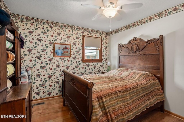 bedroom with hardwood / wood-style floors, ceiling fan, and a textured ceiling