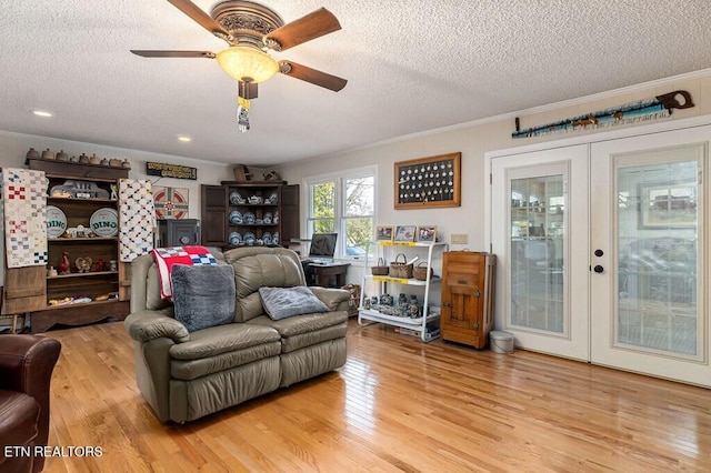 living room featuring ornamental molding, light wood-type flooring, a textured ceiling, and french doors