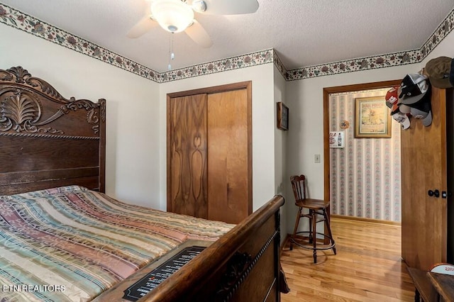 bedroom with ceiling fan, light wood-type flooring, a textured ceiling, and a closet