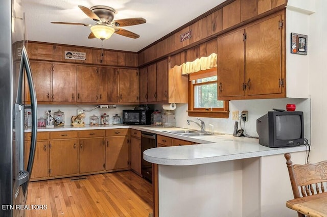 kitchen with kitchen peninsula, light wood-type flooring, ceiling fan, sink, and black appliances