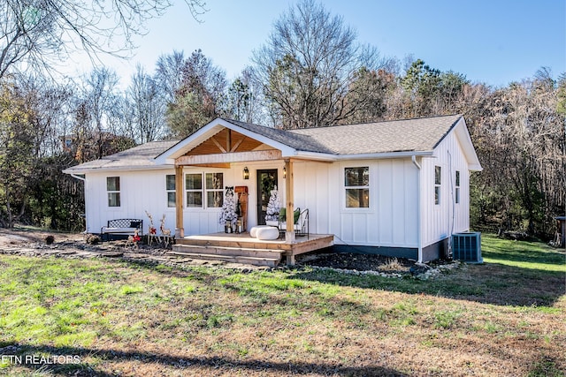 view of front facade featuring cooling unit, covered porch, and a front lawn