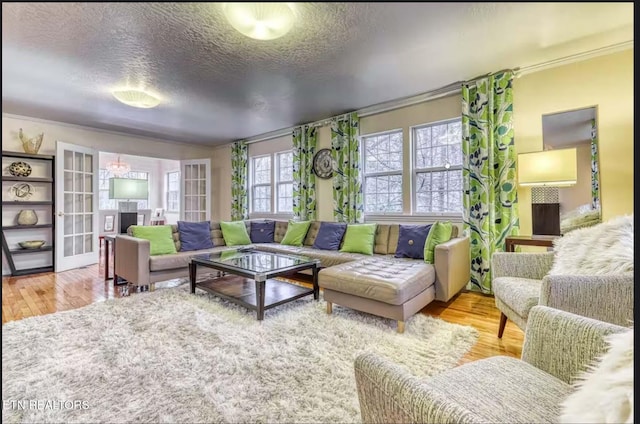 living room with light hardwood / wood-style flooring, a textured ceiling, and ornamental molding