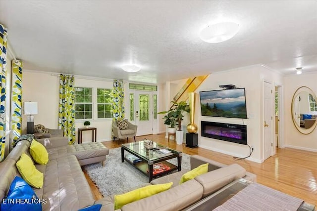 living room with a textured ceiling, light wood-type flooring, french doors, and crown molding