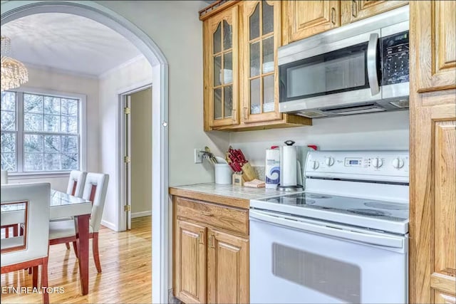 kitchen featuring crown molding, white electric range oven, and light wood-type flooring