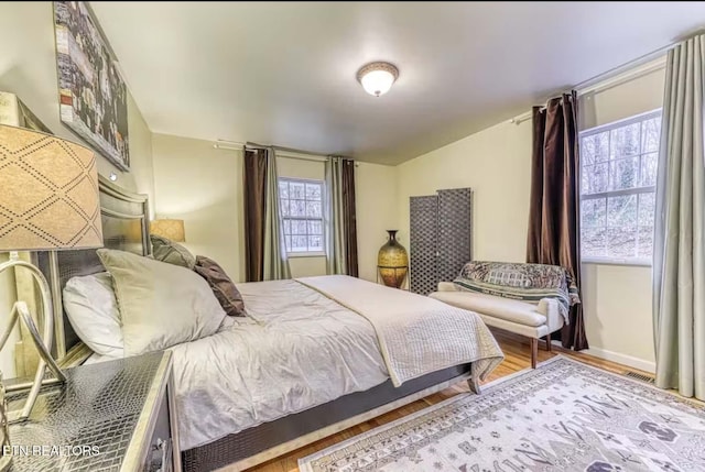 bedroom with hardwood / wood-style floors and multiple windows