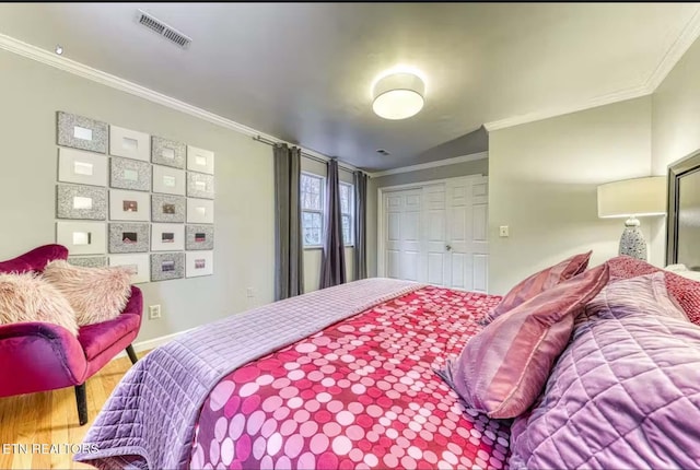 bedroom featuring hardwood / wood-style floors, vaulted ceiling, a closet, and ornamental molding