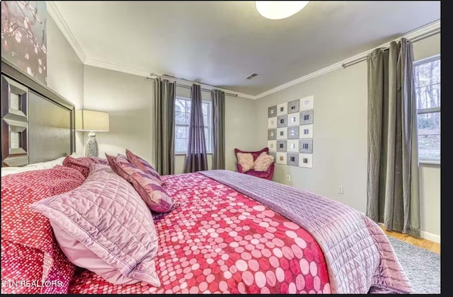 bedroom with hardwood / wood-style floors, ornamental molding, and multiple windows