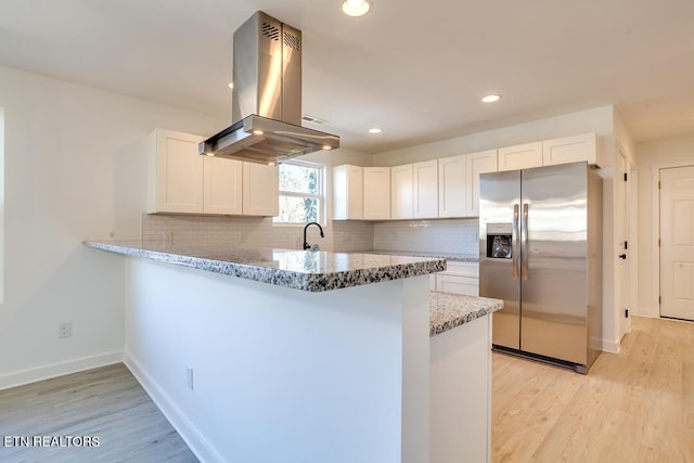 kitchen with white cabinets, stainless steel fridge with ice dispenser, island range hood, and light hardwood / wood-style floors