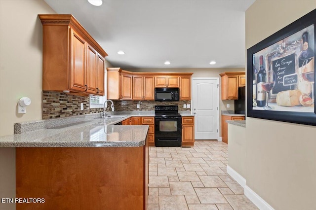 kitchen with light stone countertops, sink, kitchen peninsula, decorative backsplash, and black appliances